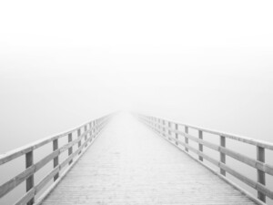 Vom Betrachter wegführende Brücke die im Nebel verschwindet