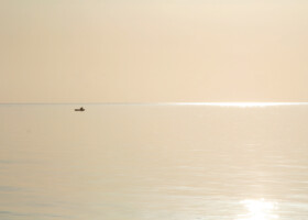 Ruhiges Meer mit einzelnem Schiff am fernen Horizont